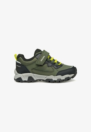 Scarpa atletica verde e nera con un esterno testurizzato, lacci elastici, cinturino in velcro e una suola grigia robusta con battistrada nero.