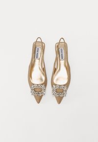 Kengät slingback -tyyliin, joissa on terävä kärki ja metallinhohtoinen kultainen kangas, koristeltuna jalokiviponnella ja sileällä, heijastavalla pohjalla.
