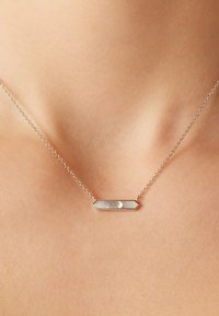 Zilveren halsketting met een hexagonaal hanger met een parelmoer inleg, bevestigd aan een fijne ketting. Elegante en minimalistische vormgeving.