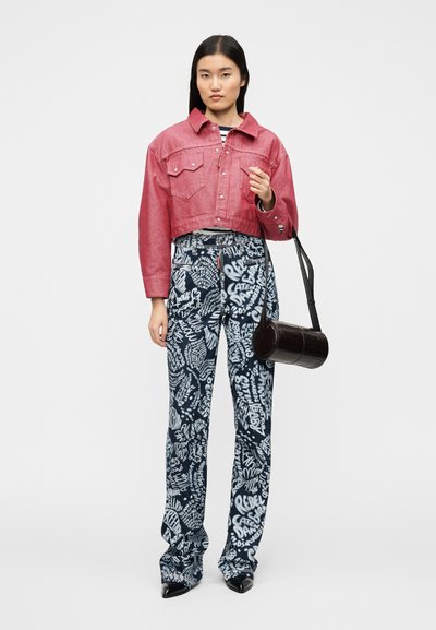 Veste en jean rouge courte avec détail à boutons, chemise rayée en dessous, pantalon large bleu à motifs, et sac rond noir.