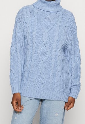 Suéter de punto azul claro con un cuello alto acanalado. Presenta patrones de punto trenzado y un corte relajado. Textura suave y mangas largas.