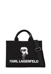 Black canvas tote bag featuring a cartoon graphic of a figure in sunglasses and white hair. "KARL LAGERFELD" printed in bold white letters.