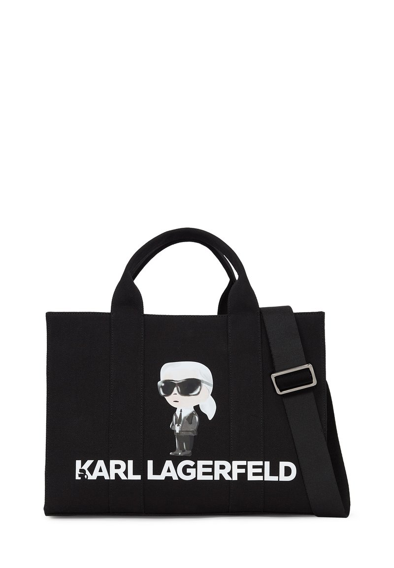Sac fourre-tout noir en toile présentant un graphique de dessin animé d'une figure portant des lunettes de soleil et ayant les cheveux blancs. "KARL LAGERFELD" imprimé en lettres blanches en gras.