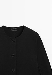 Cardigan nero lavorato a maglia con scollo rotondo e tre bottoni neri sulla parte anteriore, realizzato in 100% cotone.
