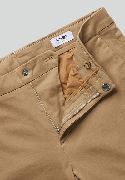 Beige katoenen broek met een rits- en knoopsluiting. De gevoerde binnenkant bestaat uit lichtbruin stof. Het label toont "NN07 No Nationality."