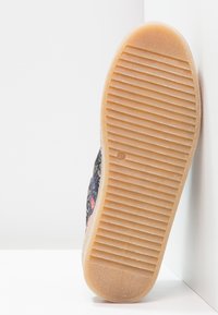 Semelle de chaussure avec une surface texturée et striée. Caoutchouc gomme semi-transparent avec un design durable, présentant un profil plat et une légère courbure.