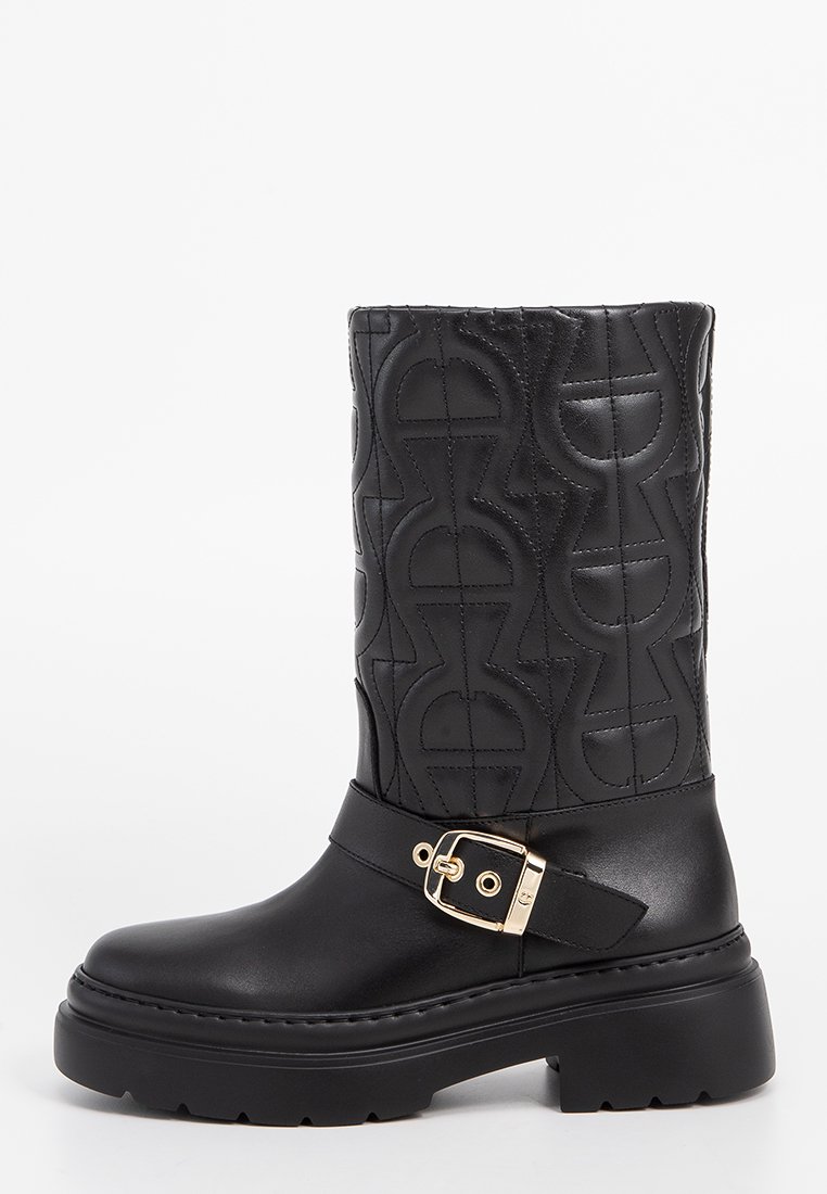 Schwarze Lederstiefel in knöchellanger Höhe mit einem gesteppten Muster, einer robusten Sohle und einem goldenen Schnallenakzent am Knöchelriemen.