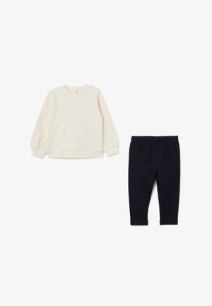 Sweatshirt crème avec un design de nœud texturé, associé à un legging navy. Les deux sont fabriqués en tissu doux, avec une taille élastique et des poignets côtelés.