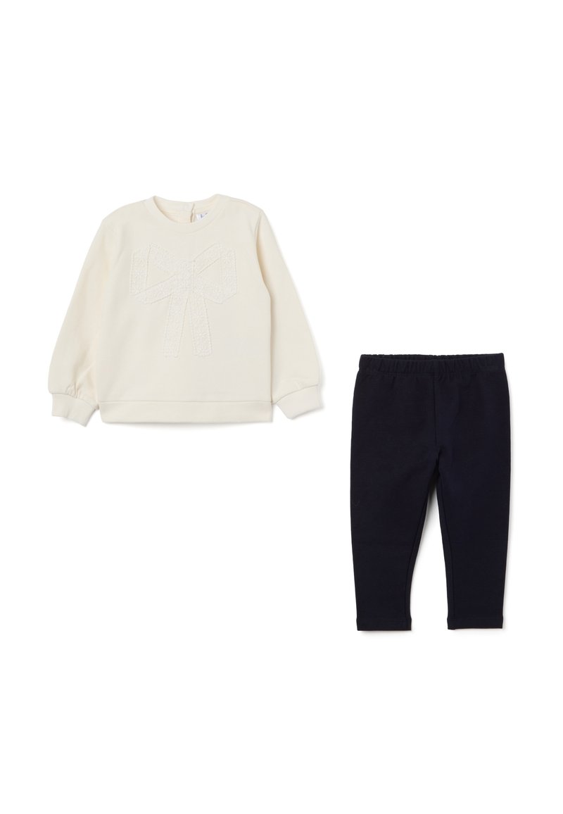 Cremefarbener Sweatshirt mit strukturiertem Schleifenmuster, kombiniert mit marineblauen Leggings. Beides besteht aus weichem Material und verfügt über einen elastischen Bund sowie gerippte Bündchen.