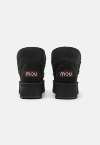 Zwarte suède enkellaarzen met een gestructureerde achterkant, een paarse label met het opschrift "mou" en een blokhak. Het ontwerp heeft ingewikkelde stiksels.