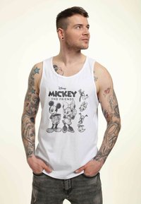 Top blanco de tirantes que presenta un gráfico de Mickey Mouse y sus amigos en blanco y negro. Material de algodón, escote redondo y corte relajado.