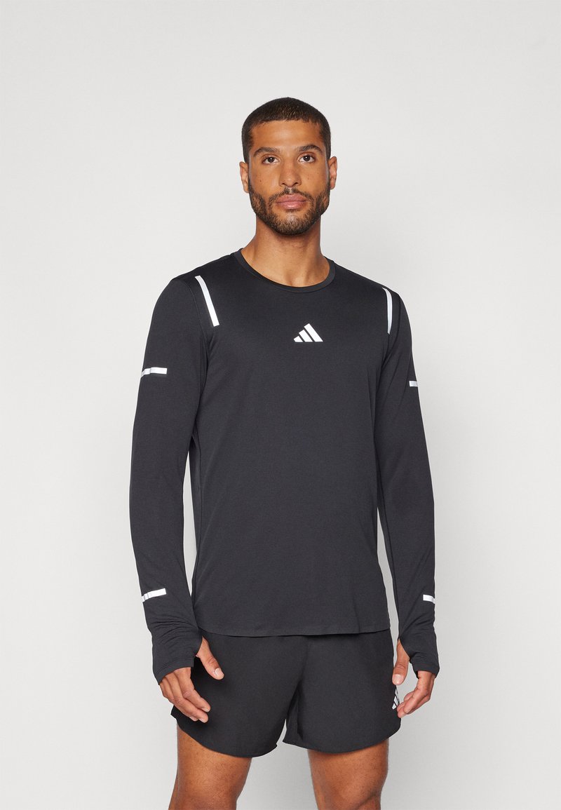 Schwarz langärmliges Sportshirt mit weißen Akzenten und dem Adidas-Logo auf der Brust, kombiniert mit schwarzen Sportshorts.