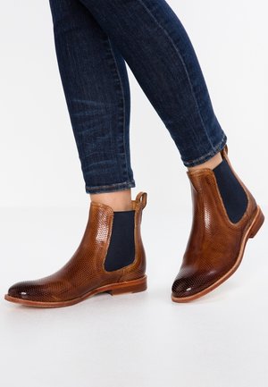Brune læder Chelsea-støvler med tekstureret mønster, elastiske sidepaneler og flade gummisåler, stylet med mørkeblå jeans.