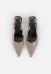 Beige leather slingback shoes with a pointed toe, open heel, and black insoles. Features a small adjustable buckle on the side.