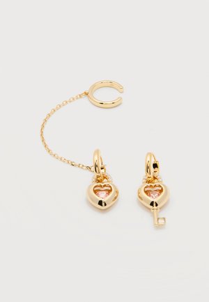 Kuldrenka kõrvarõngad südamekujuliste luku- ja võtme amuletidega, roosade kivikestega; üks kõrvarõngas ühendatud õrna kuldkettaga mansetinööbiga.