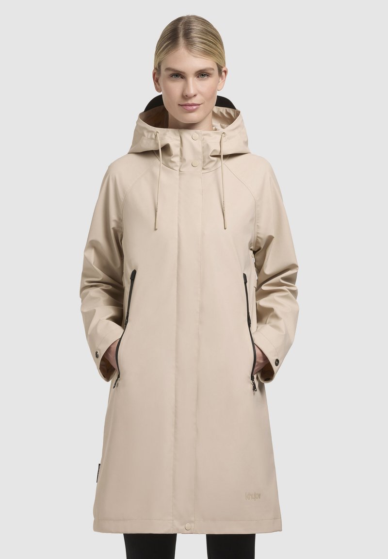 Beige waterdichte jas met een capuchon, voorzien van nietjes zijzakken, een rechte snit en een soepele textuur. Lichtgewicht en ademend ontwerp.