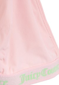 Joggers rose côtelés avec une texture lisse, présentant un logo vert sur la ceinture. Le matériau est doux et extensible, conçu pour le confort.