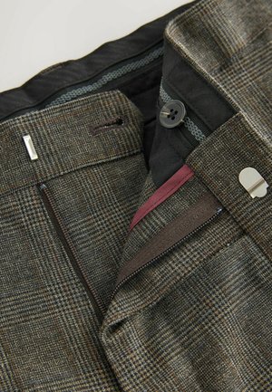 Kalhoty s hnědým a šedým kostkovaným vzorem, texturovaná vlna, zapínání na zip a knoflíky, a maroon akcent uvnitř pasu.