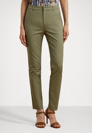 Slim-fit olijfgroene broek gedragen met bruine hoge hakken sandalen en een bloemenprint top ingestopt, van taille tot voeten getoond.