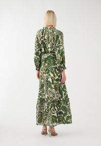 Maxikleid mit grünem Blumenmuster, langen Ärmeln, Rüschensaum und geschichtetem Saum. Hergestellt aus leichtem Stoff; hat eine taillierte Taille.