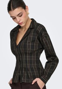 Chemise à carreaux noire à manches longues, coupe ajustée, col et boutons. Comprend des lignes multicolores en vert et bordeaux.