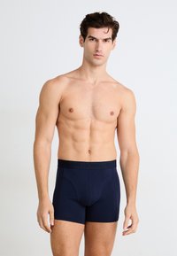 Marine-blå boksershorts med en sort elastisk linning som pryder merkevarenavnet "BORN BORG." Myk, elastisk stoff og en tettsittende design.