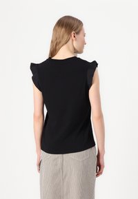 Schwarzes Kurzarmoberteil mit Rüschendetails an den Schultern, aus weichem Baumwollmaterial, lässige Passform, kombiniert mit einem gestreiften Rock, schlichte Rückansicht.