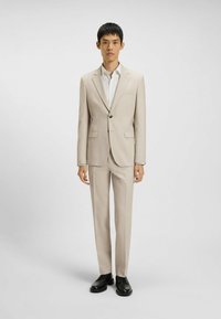 Beige jakkesæt med en enkeltknap blazer, matchende bukser og en hvid skjorte. Sorte dress sko fuldender outfittet. Glat tekstur, skræddersyet pasform.