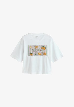 Hvid kort T-shirt med korte ærmer med broderede appelsinskiver og blade på en lyserød og grønstribet rektangulær lap.