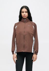 Καφέ αθλητικό μπουφάν με ψηλό γιακά, διακοσμημένο με λευκά πάνελ, κλείσιμο με φερμουάρ και ελαστικές μανσέτες. Μικρό λογότυπο στο στήθος.