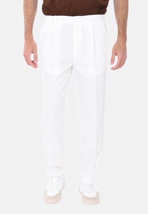 Pantaloni bianchi plissettati con un design sartoriale, realizzati in un tessuto liscio. Presentano un classico elastico in vita e tasche frontali, abbinati a sneaker.