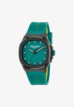 Montre bleu sarcelle avec un cadran à motif hexagonal, boîtier noir et bracelet en silicone vert texturé. Index et aiguilles blancs, logo à 12 heures.