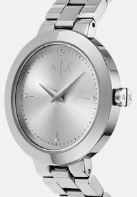 Hõbe roostevabast terasest randmevaat, ümmargune kellakujundus, minimalistlik kelladial, kristallist tunni märgid ning "A|X" logo kaheteistkümnendal kohal ja kroonil.