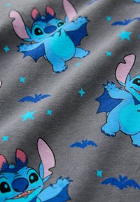 Grauer Stoff mit einem sich wiederholenden Muster aus blauen Figuren mit Fledermausflügeln, rosa Akzenten sowie kleinen blauen Sternen und Fledermäusen.