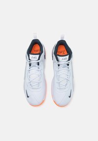 Nike sneakers with a white mesh upper, black accents, orange inner lining, and textured sole. Designed with laces and a pull tab.