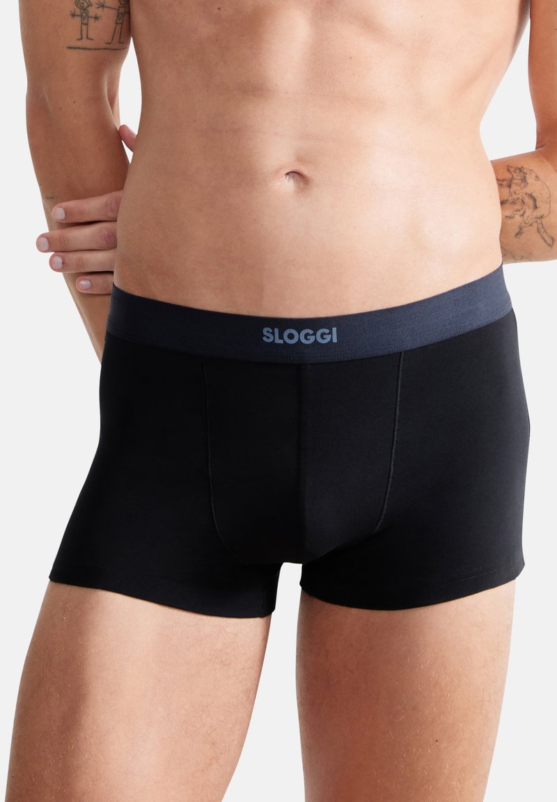 Schwarze Baumwoll-Boxershorts mit einem dunkelblauen Gummibund, der mit dem Text "SLOGGI" versehen ist. Das Design beinhaltet einen unterstützenden Frontbeutel und eine glatte Oberfläche.