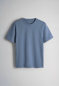 Maglietta blu semplice a maniche corte con collo a giro, appesa su uno sfondo grigio chiaro.
