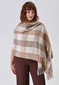 Beige en crème geruite poncho met franjes, gemaakt van zachte, warme stof. Val elegant over de schouders.