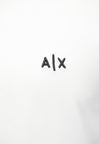 Tricou alb din bumbac, cu text brodat negru "A|X" centrat pe față. Textură netedă și design minimalist.