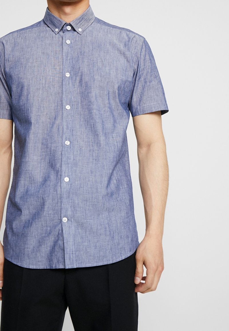 Korte mouwen overhemd met knopen in lichtblauw chambray-stof met een puntkraag, voorzien van witte knopen en een ontspannen pasvorm.