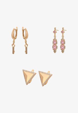 Trzy pary złotych kolczyków: wiszące w kształcie serca z kluczykiem, geometryczne z różowym kamieniem oraz trójkątne sztyfty z kryształowymi obramowaniami na białym tle.