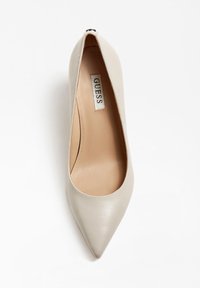 Escarpin en cuir beige à talons hauts avec un bout pointu et un design minimaliste. L'intérieur est beige; présente un logo discret sur la semelle.