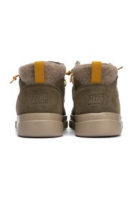 Chaussures montantes en daim marron avec doublure en fourrure, dotées de tirants jaunes et d'une semelle en caoutchouc beige. Logo de la marque embossé sur le talon.