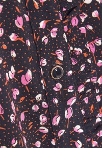 Tessuto scuro con un piccolo motivo di fiori rosa e bianchi, accentuato da punti arancioni. Presenta un luccicante bottone d'oro per la chiusura.