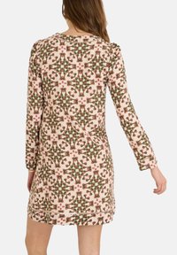 Vestido de manga larga con una base rosa y un patrón geométrico en verde y rojo. Tejido de punto con un ligero brillo y costuras decorativas.