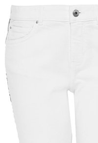 Bílé džínové kalhoty s tradičním pěti-kapsovým designem, kovovým zapínáním a jemným prošíváním. Hladká textura s úzkým střihem.