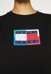 Czarna koszulka z okrągłym dekoltem i krótkimi rękawami, z prostokątnym graficznym wzorem w kolorach niebieskim, czerwonym, różowym i białym, z napisem "TOMMY JEANS".