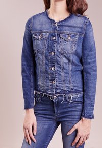 Blå denimjacka med rå fåll, fyra frampocket, knappstängning och fransig krage. Har en figurnära design och texturerat tyg.