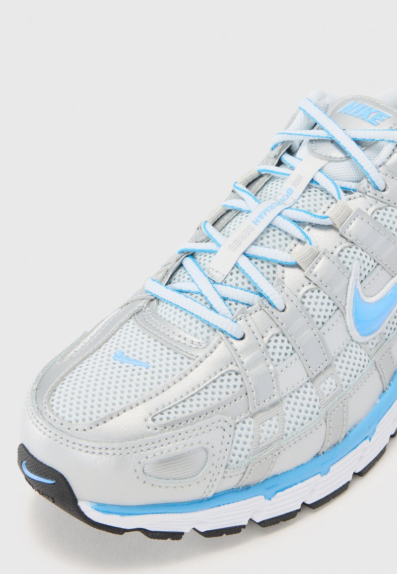 Chaussure de course Nike avec une tige en maille gris clair et des accents bleus, des superpositions à motifs et une semelle extérieure en caoutchouc noir.