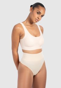 Beżowy bezszwowy biustonosz z szerokimi ramiączkami, zaprojektowany z myślą o komforcie, w komplecie z wysokim stanem figami w dopasowanym odcieniu, charakteryzującymi się miękkim, gładkim materiałem.